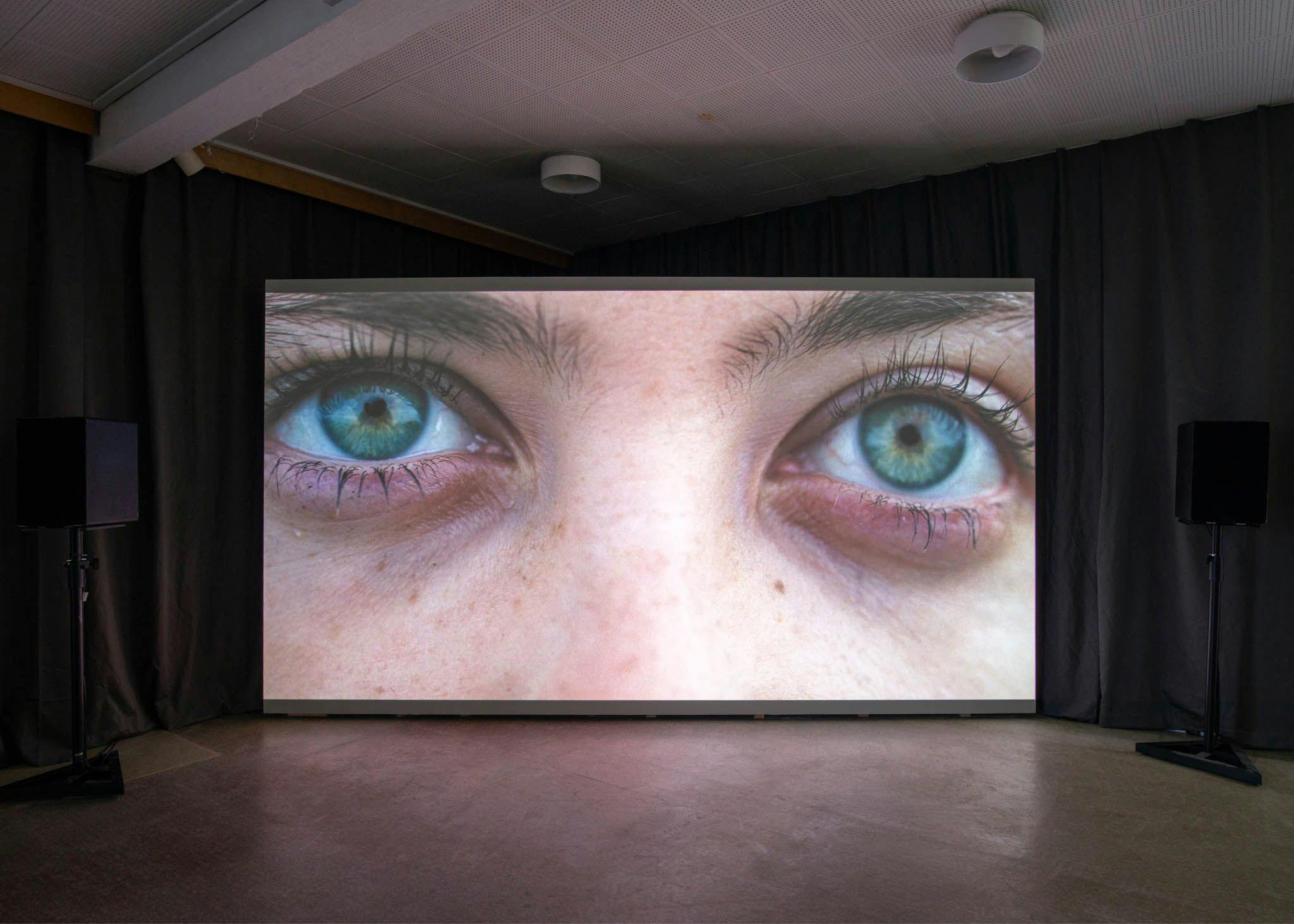 Two green eyes stare out from a projector screen