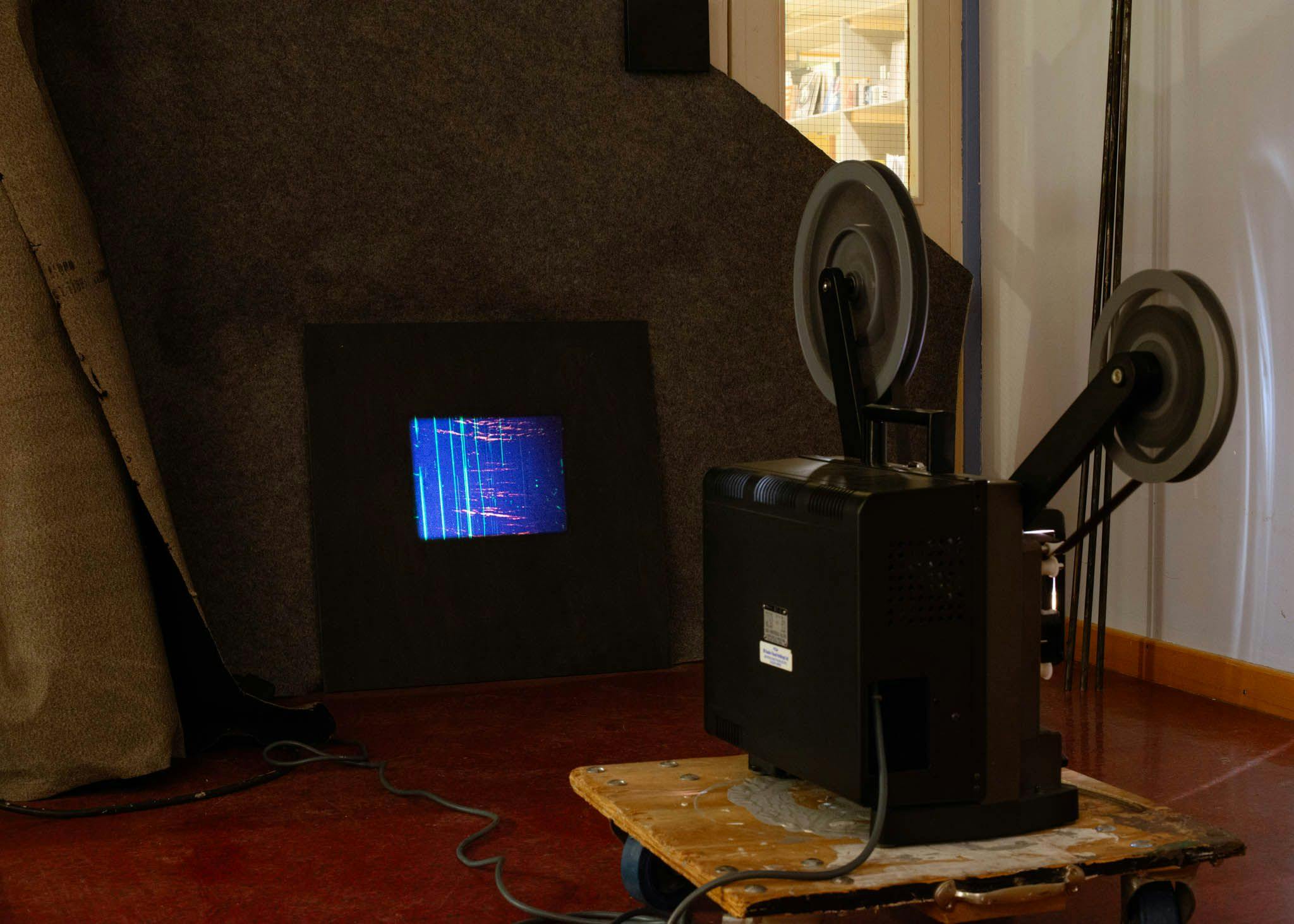 An analogue projector shows a blue image in a dark room.